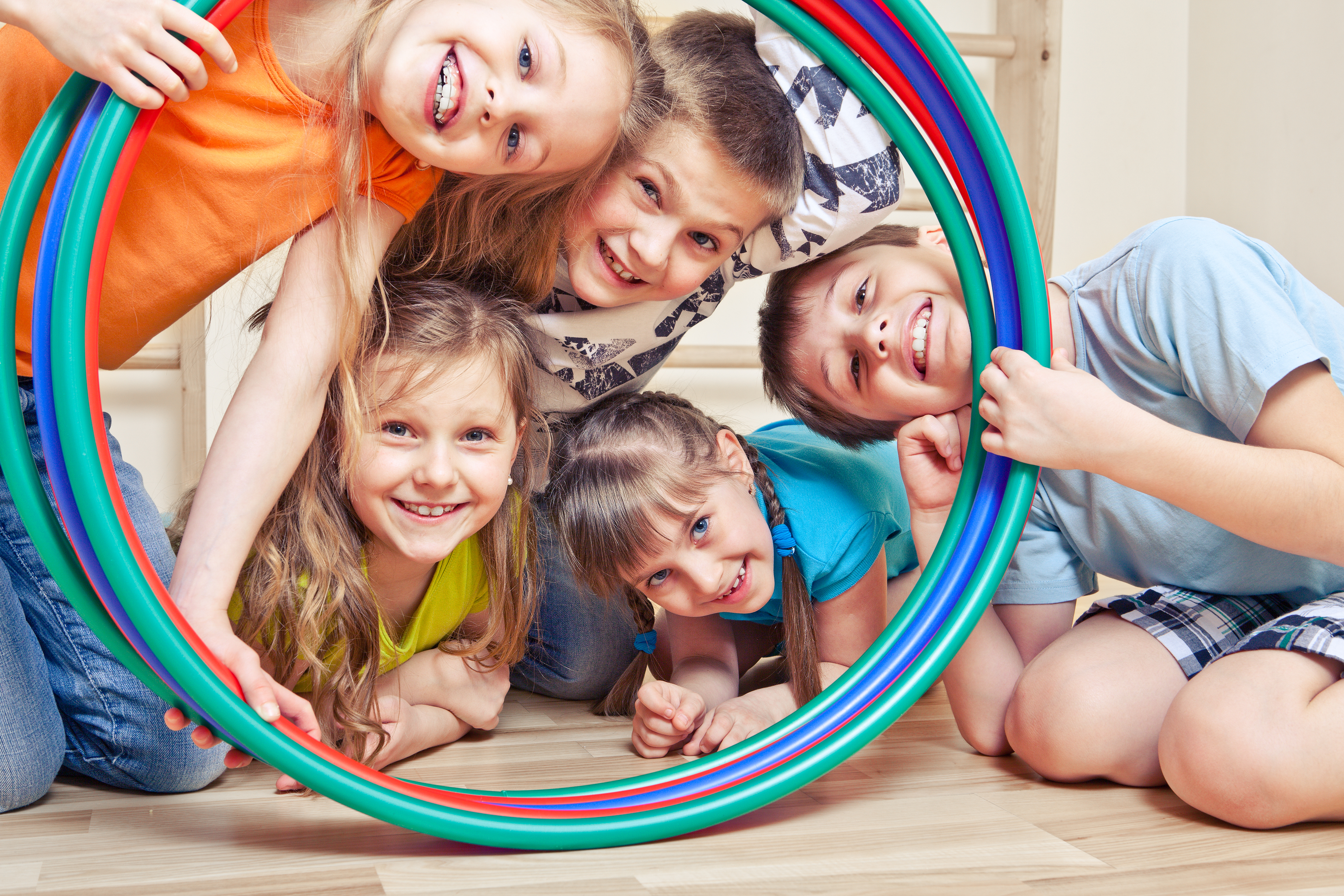 Group of children smiling, looking through hula hoop