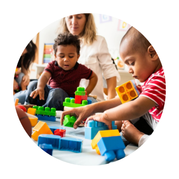 Toddlers sitting on floor with parents/childcare providers playing with colourful building blocks in nursery room