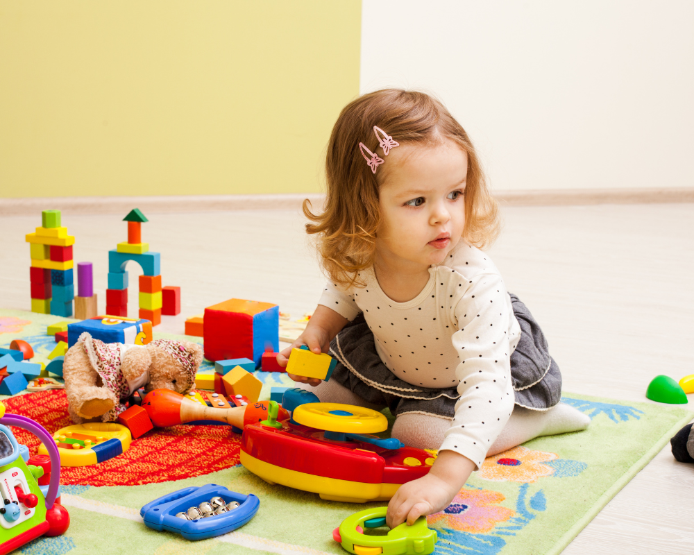 Toddler playing with colourful toys on play mat 
