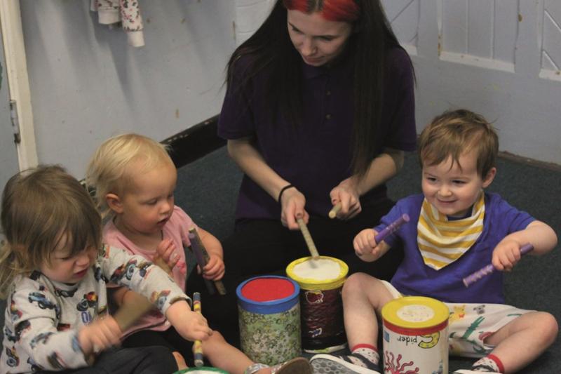 Boogie Mites teacher playing instruments with 3 toddlers in music class