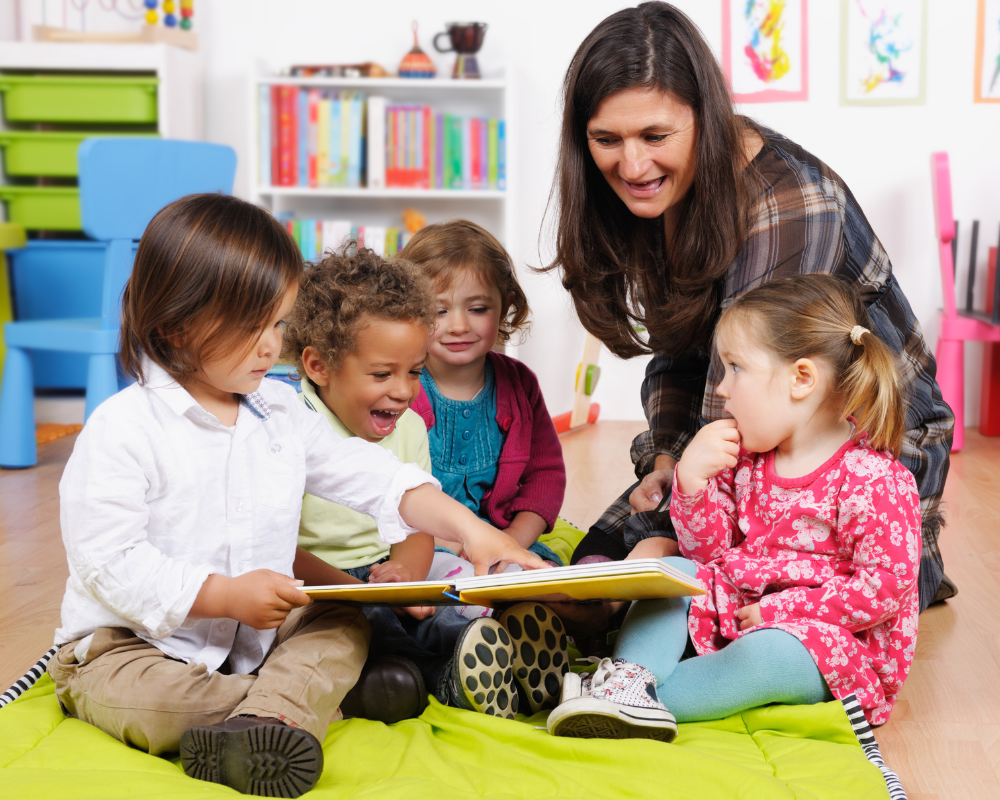 Group of little children enjoying storytime in a nursery setting with their carer 