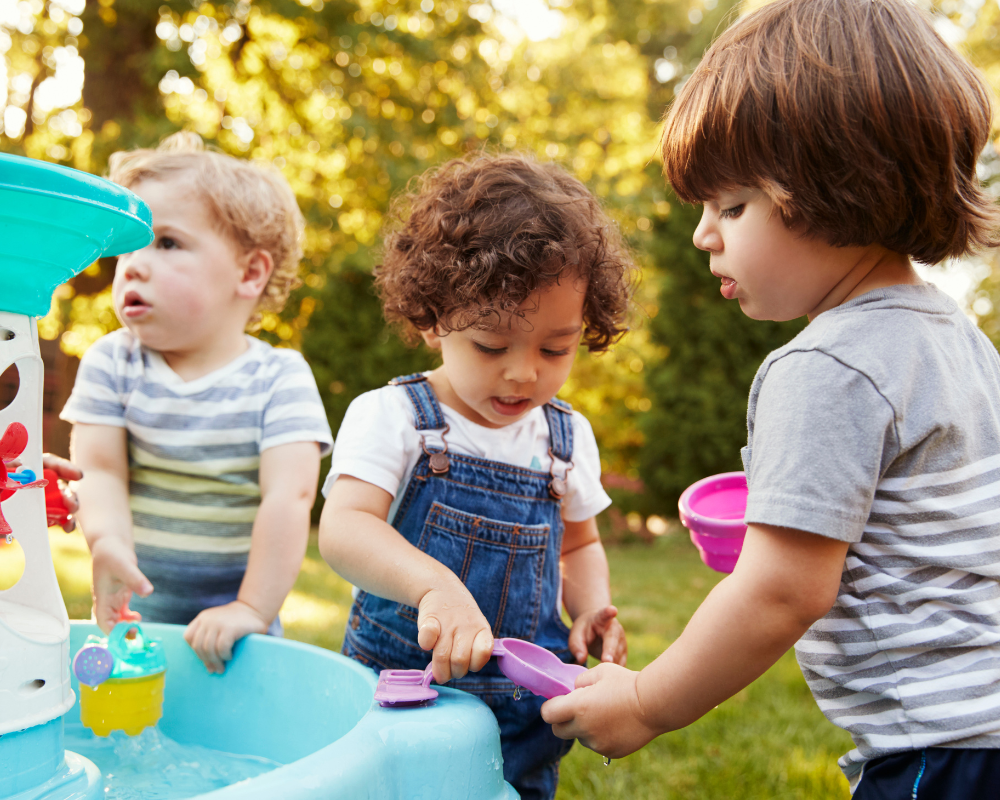 Group of young children playing with water table outdoors 