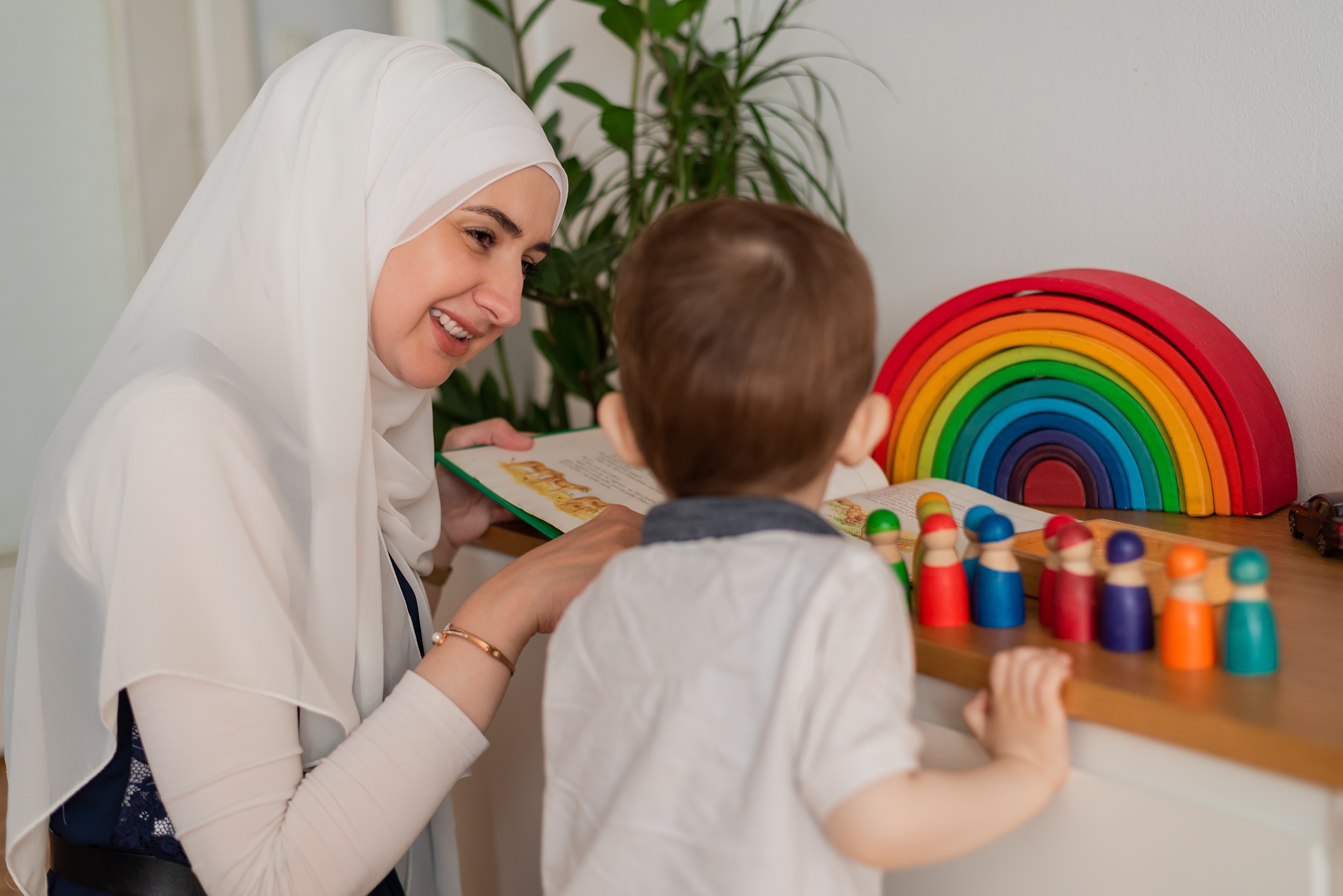 Teacher and preschool child playing together with colourful toys in the Montessori school classroom or kindergarten.