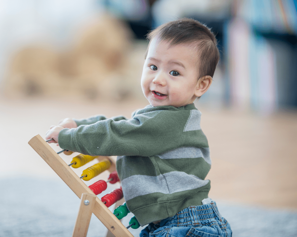 Toddler smiling and playing with abacus