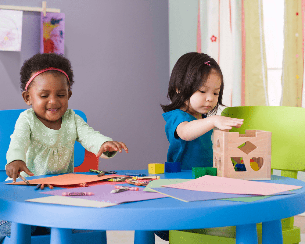 Two toddlers colouring and playing with blocks at daycare