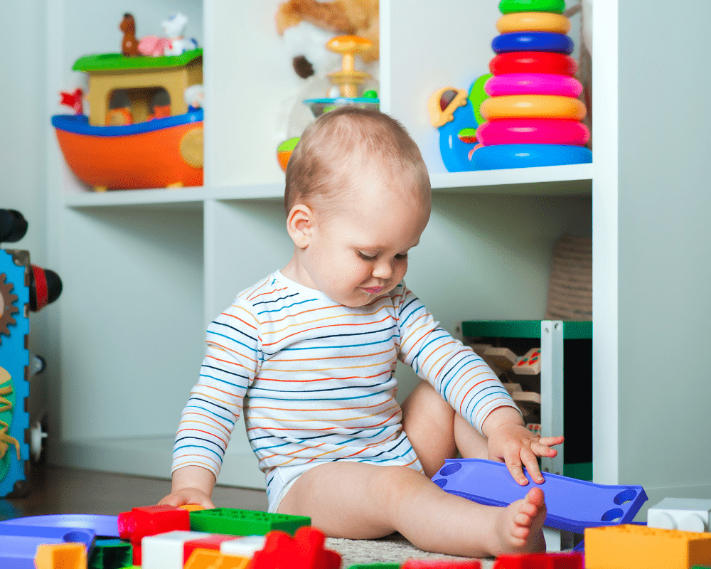 Toddler sitting on floor playing with colourful toys