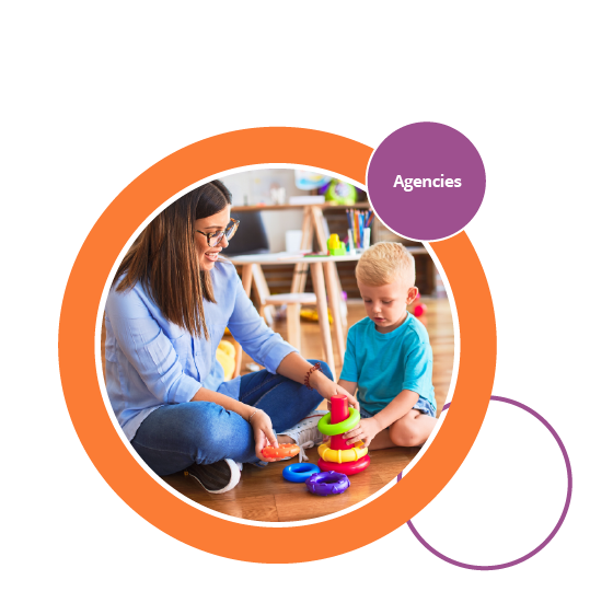 Roundel image showing childcare provider playing with young child on the floor in a preschool or nursery classroom with colourful toys 